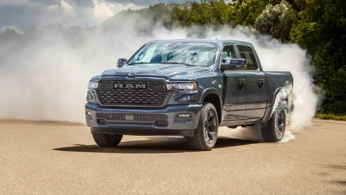 A blue RAM 1500 turning up dust and smoke as it drives in a test field