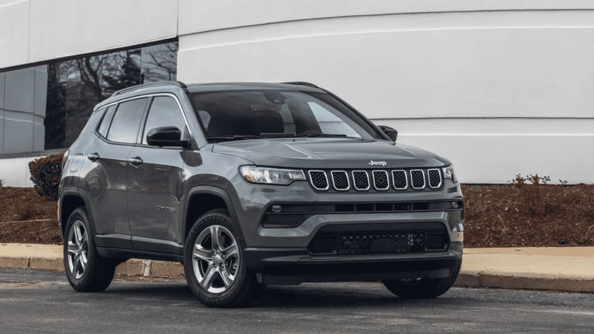 A gray Jeep Compass parked by the curb outside a building