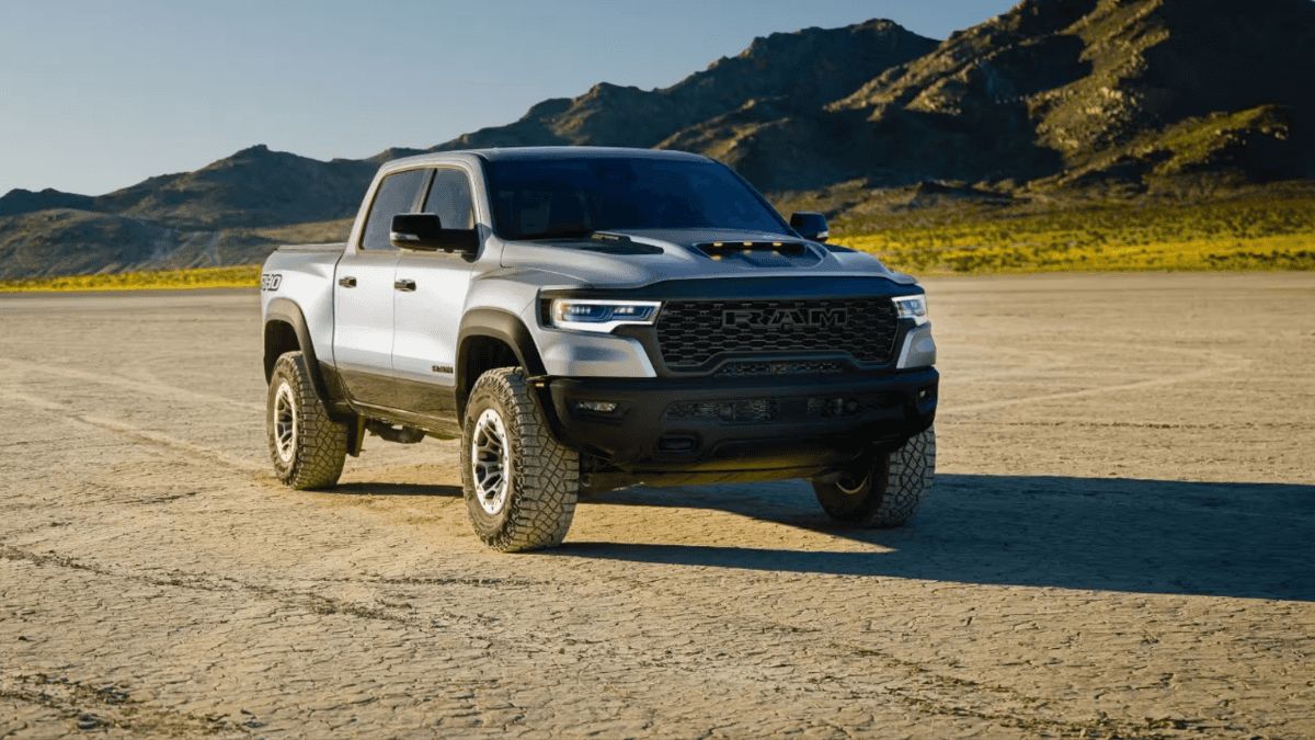 A light blue RAM 1500 in the middle of a dirt area near a mountain