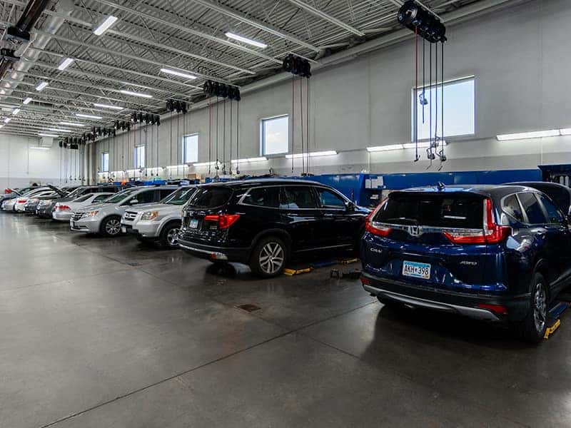 Vehicles receiving maintenance inside a dealership automotive service bay