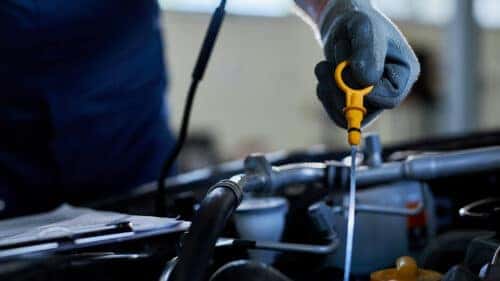Checking engine oil level with dipstick during routine car maintenance