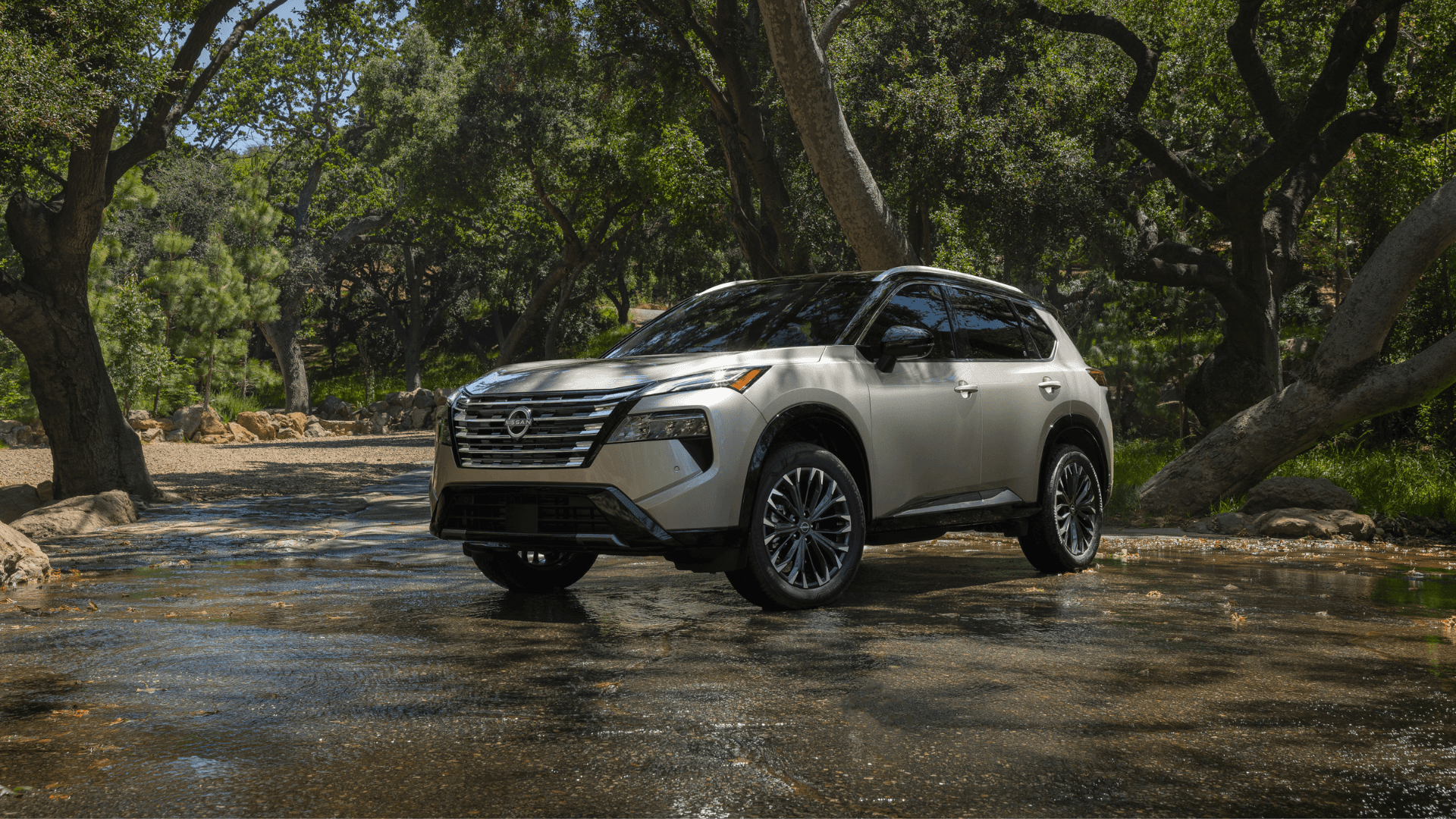 2025 Nissan Rogue driving down a country road.