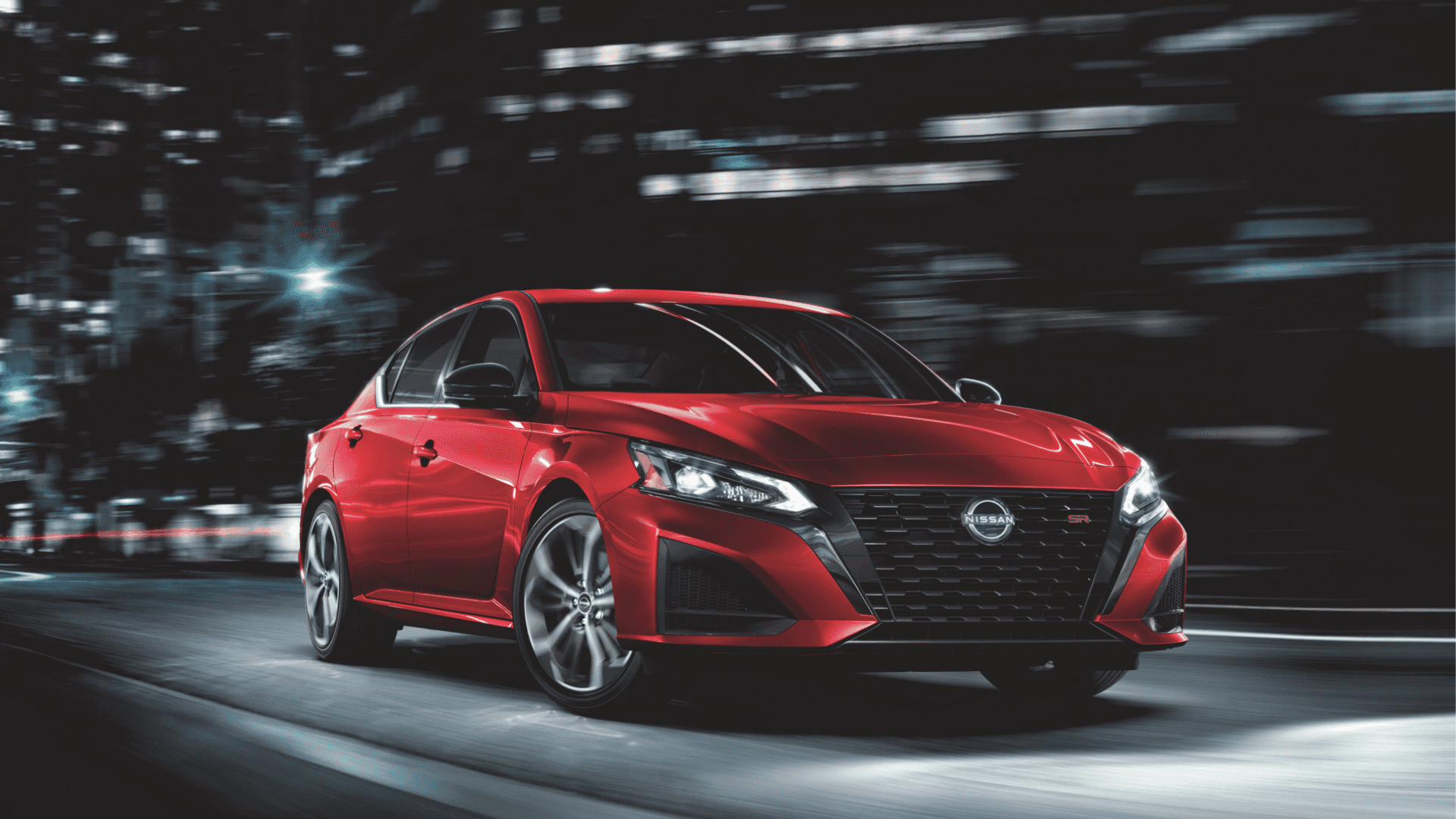 Red 2025 Nissan Altima driving through a city at night.