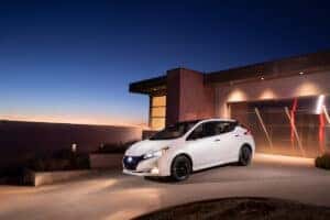White 2024 Nissan Leaf parked in front of a home at dusk