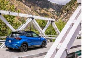 Blue 2024 Nissan Kicks driving across a bridge