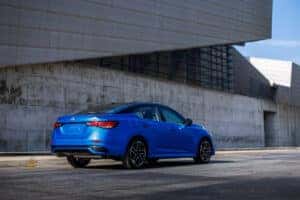 Blue 2024 Nissan Sentra facing away in front of an industrial building