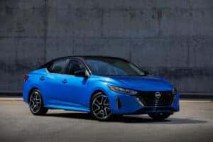 Blue 2024 Nissan Sentra parked in front of industrial area