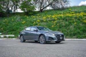 Silver 2024 Nissan Altima parked in front of a grassy hill
