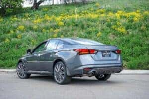 Back end of a silver 2024 Nissan Altima parked in front of a grassy hill