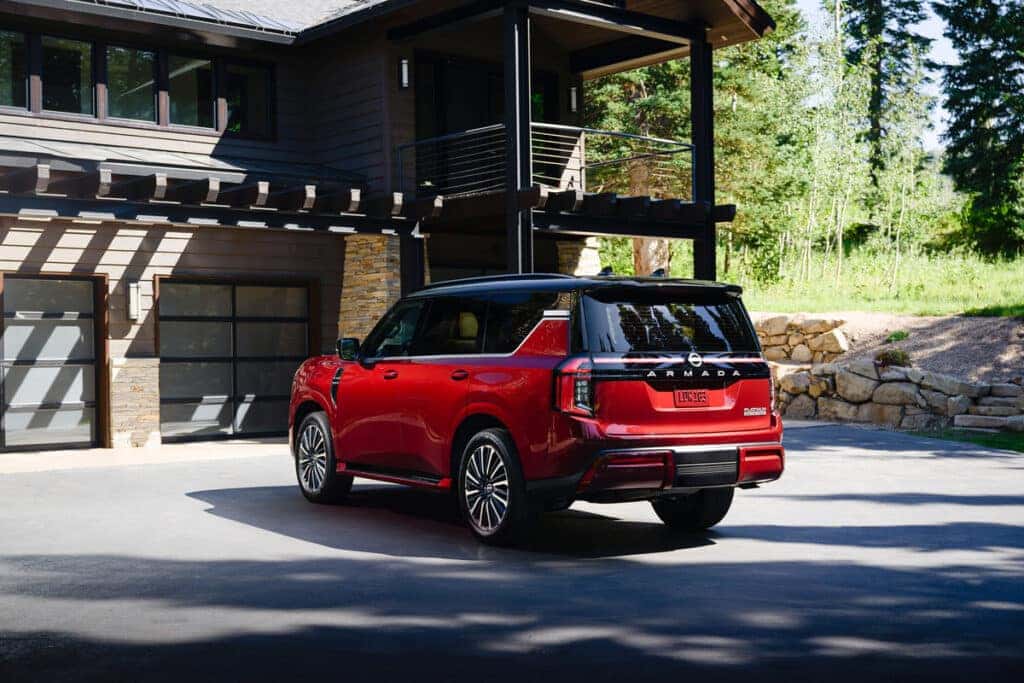 Red 2025 Nissan Armada Platinum Reserve Parked in front of a garage